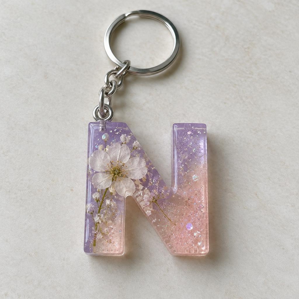 Porte-clés initiale N en résine transparente rose et violette avec fleur blanche